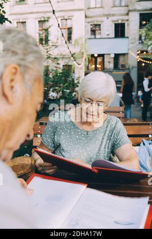 Un homme et une femme de premier plan lisant le menu tout en étant assis au restaurant en ville Banque D'Images