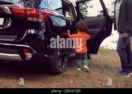 Homme regardant son fils debout près de la porte de voiture au camping Banque D'Images