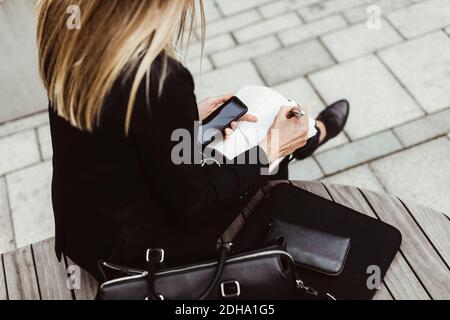 Section basse de femme d'affaires écrivant tout en étant assise à l'extérieur Banque D'Images