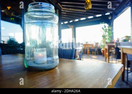 Une bougie illuminée dans le pot en verre sur la table Banque D'Images