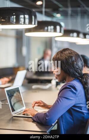 Femme d'affaires travaillant sur un ordinateur portable assis à une table au bureau Banque D'Images