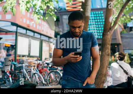 Jeune homme utilisant un smartphone en ville Banque D'Images