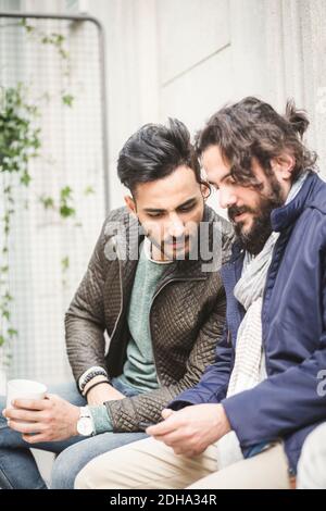 Jeune homme d'affaires montrant le téléphone portable à un collègue pendant qu'il est assis dans le bureau créatif Banque D'Images