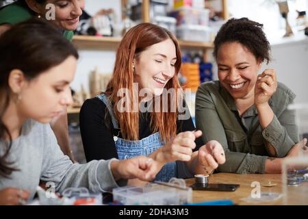 Des femmes d'ingénieurs gaies à table en atelier Banque D'Images