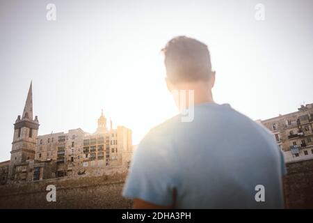 Vue arrière de l'homme regardant le bâtiment dans la ville contre ciel Banque D'Images