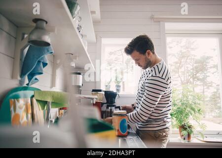 Vue latérale de l'homme faisant du café dans la cuisine à la maison Banque D'Images