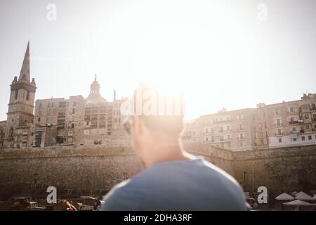 Vue arrière d'un homme mature qui regarde le bâtiment de la ville contre le ciel Banque D'Images