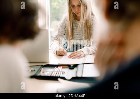 Female student writing in book at table Banque D'Images