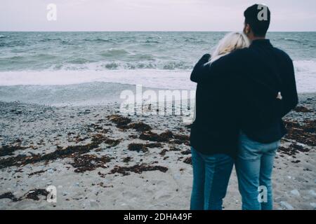 Vue arrière d'un jeune couple se tenant sur la rive à la plage Banque D'Images