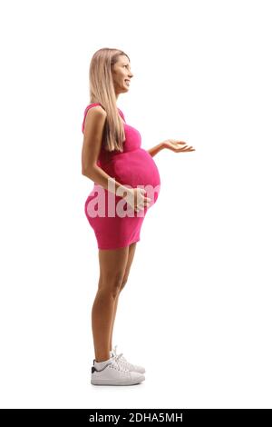 Photo de profil pleine longueur d'une jeune femme enceinte dans robe rose isolée sur fond blanc Banque D'Images