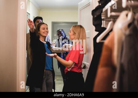 Des amies souriantes se embrassant en se tenant debout devant les hommes Banque D'Images