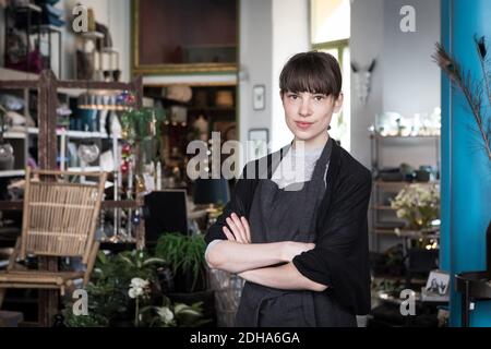 Portrait d'une jeune entrepreneur confiante debout avec les bras croisés en magasin Banque D'Images