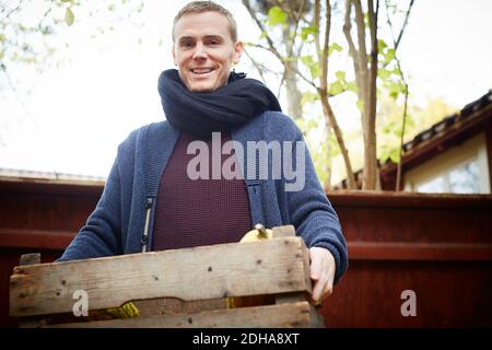 Portrait de l'homme heureux debout avec panier de légumes à l'arrière cour Banque D'Images