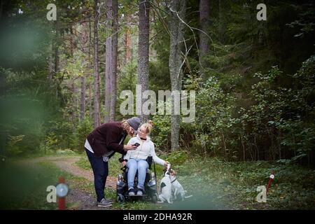 Gardien mâle avec femme handicapée utilisant un téléphone mobile dans la forêt Banque D'Images