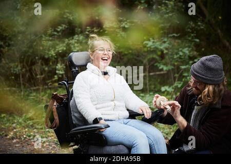 Femme joyeuse en fauteuil roulant avec un gardien tenant un champignon à forêt Banque D'Images