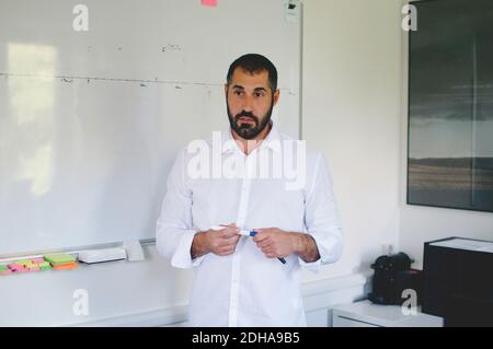 Homme d'affaires mûr debout contre le tableau blanc tout en donnant la présentation dans la créativité bureau Banque D'Images