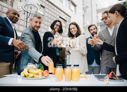 Souriant hommes et femmes cadres d'affaires avec jus de fruit à l'extérieur du bureau Banque D'Images