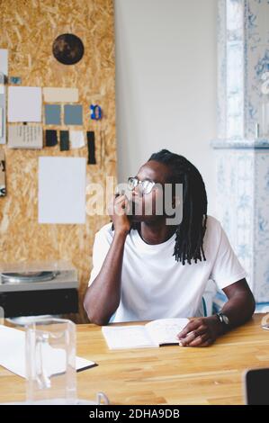Un jeune homme d'affaires attentionné assis avec la main sur le menton à table dans le bureau créatif Banque D'Images