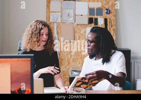 Un jeune homme d'affaires et une femme d'affaires discutent dans un bureau créatif Banque D'Images