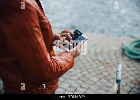 Section médiane d'une femme âgée utilisant un téléphone mobile sur le trottoir Banque D'Images