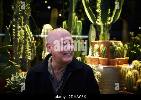 Homme de haut niveau souriant assis contre un magasin d'usine succulent la nuit Banque D'Images