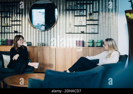 Deux collègues souriants assis à une table basse dans le bureau Banque D'Images