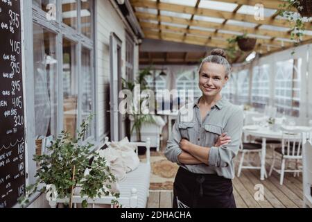 Portrait d'une femme d'affaires souriante aux bras croisés debout au restaurant Banque D'Images