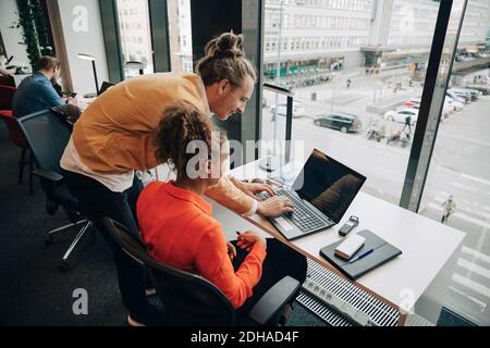 Vue en grand angle de l'homme d'affaires tapant sur un ordinateur portable par femme d'affaires au bureau Banque D'Images