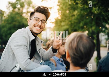 Portrait d'un jeune homme qui gestuelle assis à l'extérieur Banque D'Images