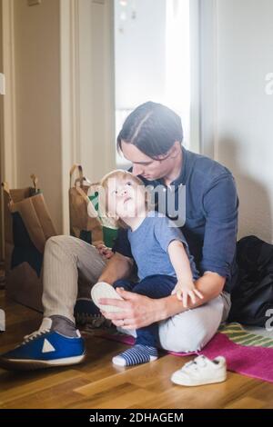 Bébé garçon regardant le père aider à porter des chaussures Banque D'Images