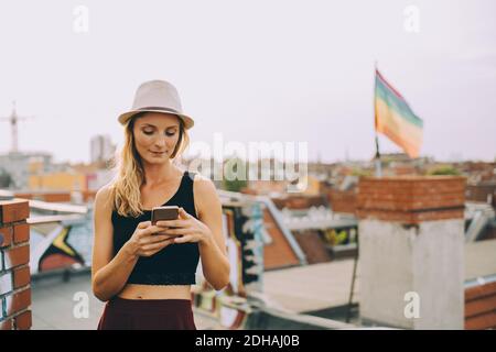 Jeune femme messagerie texte sur smartphone en terrasse en ville Banque D'Images