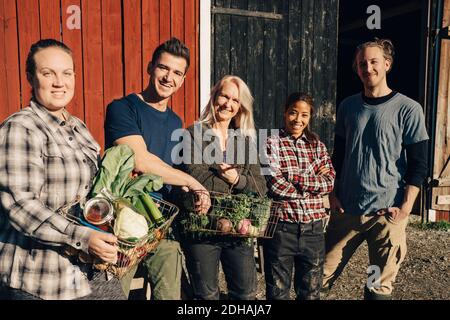 Portrait d'agriculteurs masculins et féminins avec des légumes biologiques debout grange extérieure Banque D'Images