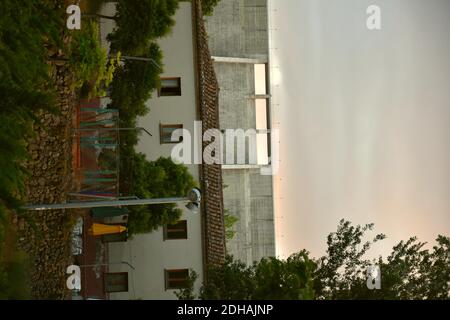 Partie du mur du barrage d'Enciso (la Rioja) derrière un bâtiment avec arbres. Banque D'Images