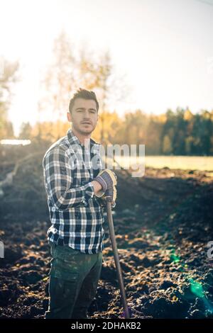 Portrait d'un fermier mâle confiant avec pelle debout sur bio ferme Banque D'Images