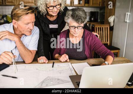 Une enseignante expliquant l'homme et la femme senior sur un ordinateur portable à tableau pendant le parcours de navigation Banque D'Images