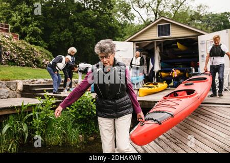 Femme et homme senior transportant du kayak sur la jetée pendant le kayak cours Banque D'Images