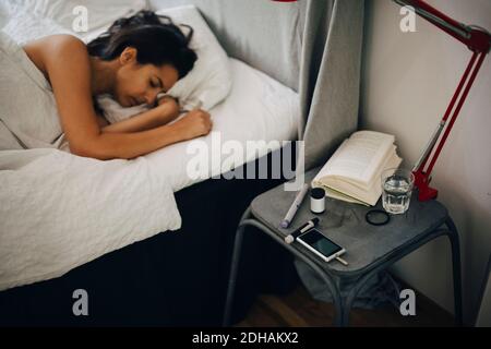 Femme couché sur le lit par kit de diabète ion chambre Banque D'Images
