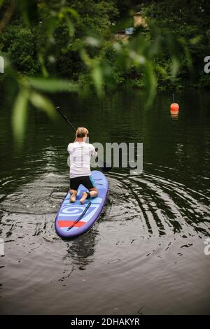 Vue arrière de l'homme senior paddleboard en mer pendant le SUP cours Banque D'Images