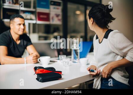 Femme d'affaires qui injecte de l'insuline tout en parlant à un collègue à table Banque D'Images