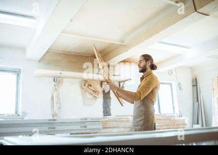 Beau menuisier vérifiant la qualité du cadre de la fenêtre avant la peinture à l'atelier de menuiserie Banque D'Images