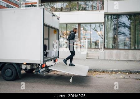 Longueur totale de travailleur masculin avec le paquet sortant de minibus de livraison en ville Banque D'Images