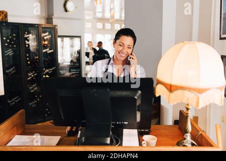 Femme souriante prenant la commande sur téléphone portable dans le restaurant Banque D'Images
