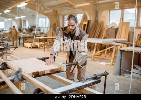 Charpentier élégant en barres de bois d'encollage uniforme avec pressions à la main à la fabrication de menuiserie Banque D'Images