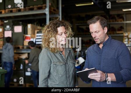 Collègues matures discutant de la tablette numérique à l'entrepôt Banque D'Images