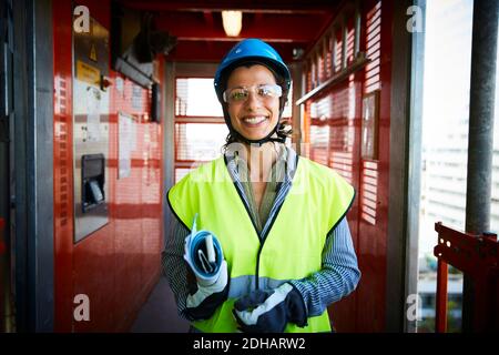 Portrait d'une femme ingénieure souriante vêque de vêtements réfléchissants lors de la construction site Banque D'Images