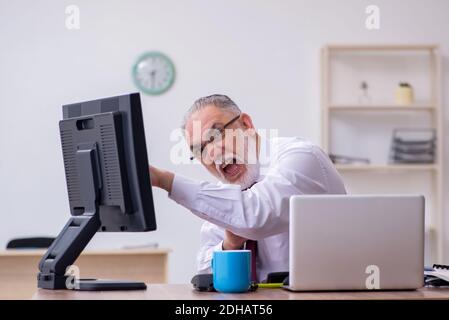 Ancien patron masculin assis au bureau Banque D'Images