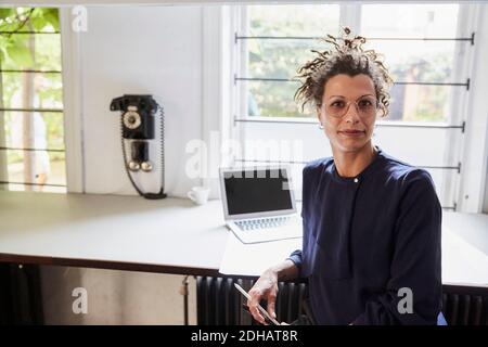 Portrait d'une femme architecte confiante assise à une table au bureau Banque D'Images