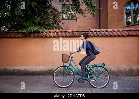 Vue latérale d'une femme architecte à vélo dans la rue ville Banque D'Images