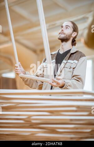 Beau menuisier vérifiant la qualité du cadre de la fenêtre avant la peinture à l'atelier de menuiserie Banque D'Images