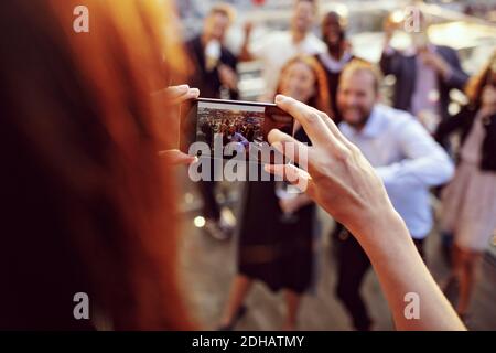 Image rognée d'un cadre photographiant des collègues sur un smartphone à terrasse dans la fête de bureau Banque D'Images